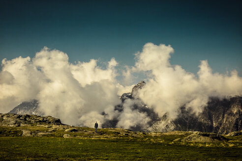 Frankreich, Lombardei, bei Chiareggio, Blick auf wolkenverhangene Alpen, einsamer Mann - DWIF000455