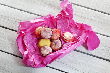 Bunte Macarons in rosa Papier auf Holz - CSF024864