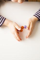 Little girl playing with chocolate buttons - LVF003027