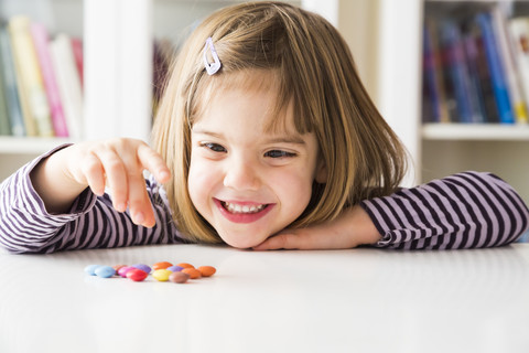 Lächelndes kleines Mädchen spielt mit Schokoladenknöpfen, lizenzfreies Stockfoto