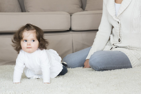Kleines Mädchen krabbelt auf Teppich, lizenzfreies Stockfoto