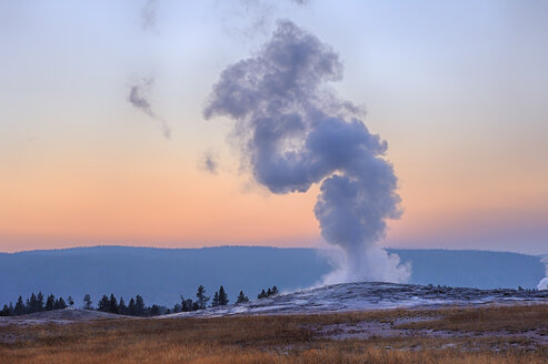 USA, Wyoming, Yellowstone National Park, Old Faithful Geysir bei Sonnenuntergang ausbrechend - RUEF001582