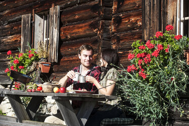 Österreich, Altenmarkt-Zauchensee, Pärchen macht Pause auf Almhütte - HHF005152