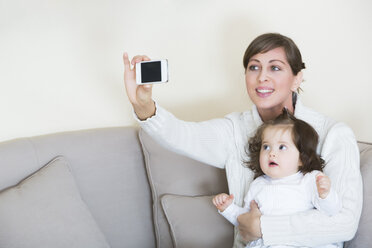 Woman taking selfie with her daughter on couch - JTLF000062
