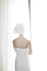 Woman wrapped in white towel standing in front of white curtain - CHPF000101
