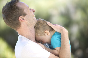 Father hugging little boy outdoors - ZEF003759