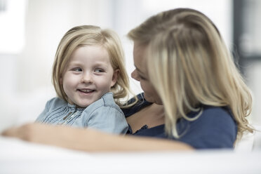 Mutter und kleine Tochter sitzen auf einer Couch und lesen ein Buch - ZEF004007