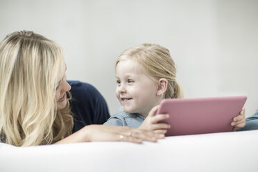 Mother and little daughter on couch with digital tablet - ZEF004011