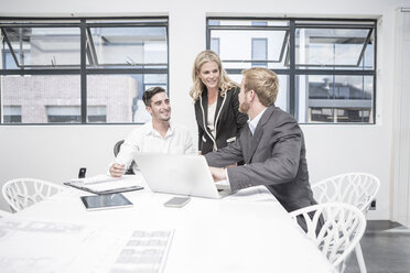 Three businesspeople having an office meeting with laptop - ZEF004524