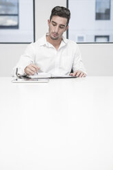 Businessman in office writing in organizer - ZEF004702