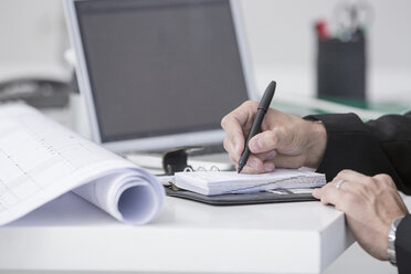 Close-up of businessman in office writing in organizer - ZEF004654