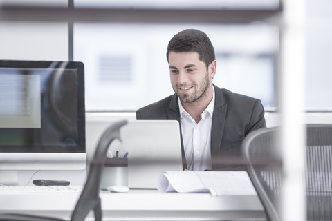 Geschäftsmann im Büro mit Laptop, lizenzfreies Stockfoto