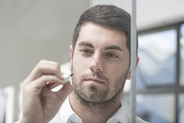 Geschäftsmann im Büro schreibt Notizen auf Glas - ZEF004673