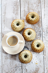 Fünf Mini-Gugelhupf mit Mohn und Kaffeetasse auf Holz - CSF024901