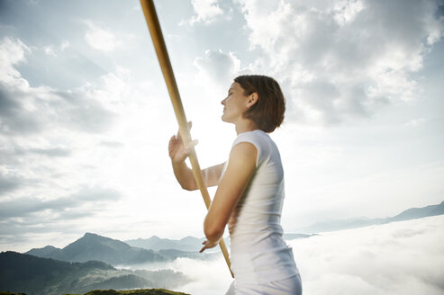 Austria, Kranzhorn, Mid adult woman exercising stick fighting on mountain top - MAOF000006