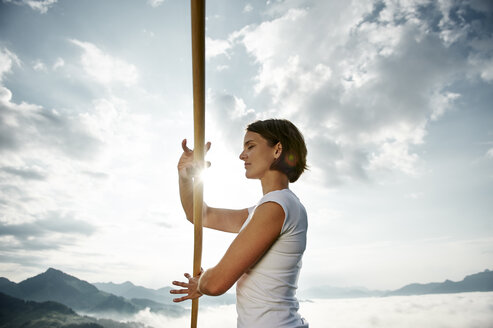 Austria, Kranzhorn, Mid adult woman exercising stick fighting on mountain top - MAOF000007