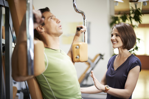 Mann arbeitet mit Trainer im Fitnessstudio, lizenzfreies Stockfoto