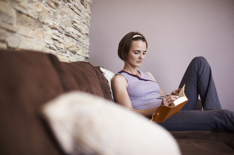 Woman sitting on couch taking notes stock photo