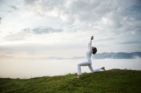 Austria.Kranzhorn, Mid adult woman practising yoga on mountain top stock photo