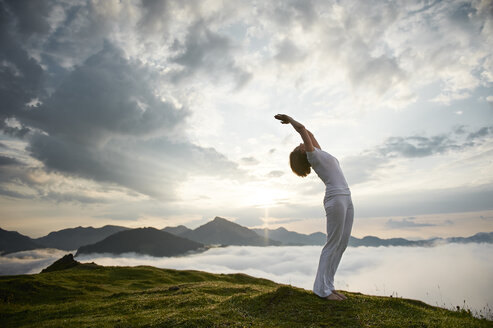 Austria.Kranzhorn, Mid adult woman practising yoga on mountain top - MAOF000017