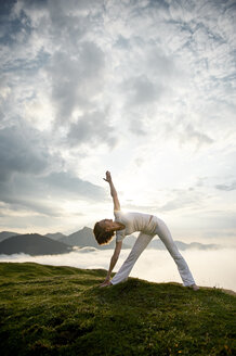 Austria.Kranzhorn, Mid adult woman practising yoga on mountain top - MAOF000020