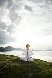 Austria.Kranzhorn, Mid adult woman practising yoga on mountain top - MAOF000024