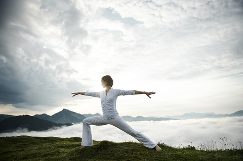 Austria.Kranzhorn, Mid adult woman practising yoga on mountain top stock photo