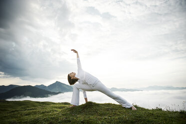 Austria.Kranzhorn, Mid adult woman practising yoga on mountain top - MAOF000027