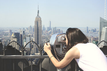 USA, New York, Frau schaut durch ein Fernglas auf Manhattan mit Empire State Building - GEMF000113