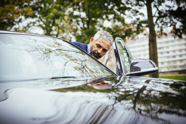 Mann steigt in sein Auto ein - MBEF001332