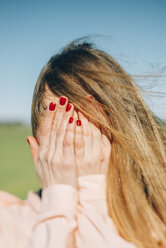 Junge Frau mit lackierten Nägeln, die ihr Gesicht bedecken - JPF000029