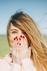 Porträt einer jungen Frau mit vom Wind zerzausten langen Haaren und lackierten Fingernägeln - JPF000032
