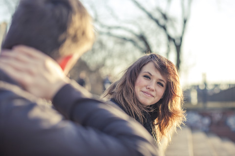 Germany, Berlin, portrait of smiling teenage girl watching boyfriend stock photo