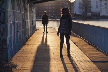 Deutschland, Berlin, jugendliches Paar unter einer Brücke im Abendsonnenlicht - MMFF000529