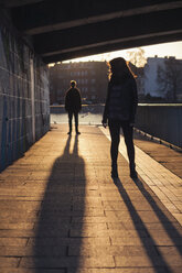 Deutschland, Berlin, jugendliches Paar unter einer Brücke im Abendsonnenlicht - MMFF000519