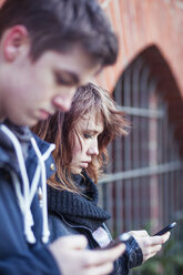 Teenager-Mädchen mit Smartphone, Junge unscharf im Vordergrund - MMFF000510