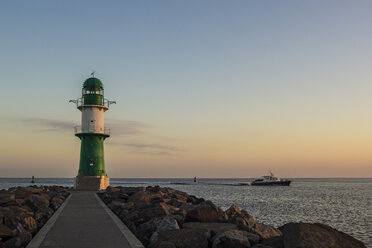 Deutschland, Warnemünde, Leuchtturm am frühen Morgen mit einem einlaufenden Boot - MELF000046