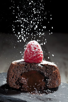 Geschnittene kleine Schokoladentorte mit geschmolzener Schokoladenfüllung, garniert mit Himbeeren - CSF024959