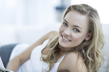 Porträt einer lächelnden blonden Frau, die auf einer Couch liegt - ZEF003625