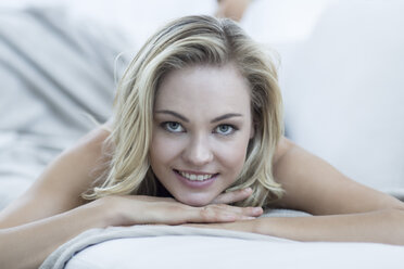 Portrait of smiling blond woman lying on a couch - ZEF003636