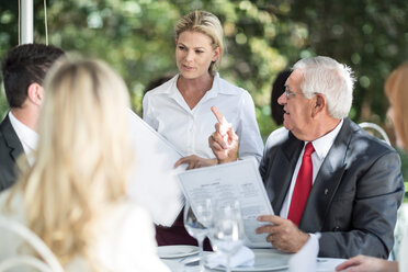 Waitress explaining menu to clients at table - ZEF004115