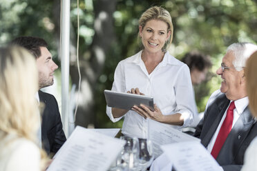 Waitress taking clients lunch orders at table using a digital tablet - ZEF004157