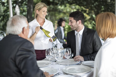 Waitress showing white wine to clients at table - ZEF004121