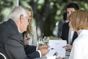 Elegante Menschen in einem Außenrestaurant, die einen Vertrag besprechen - ZEF004162