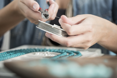Nahaufnahme einer Frau, die mit einer Zange arbeitet, um eine Perlenkette herzustellen, lizenzfreies Stockfoto