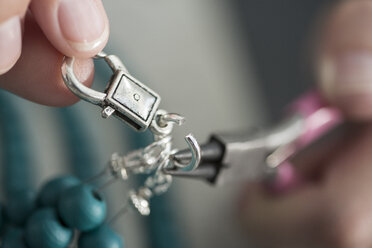 Nahaufnahme einer Frau, die mit Perlen arbeitet, um eine Halskette herzustellen - ZEF003646