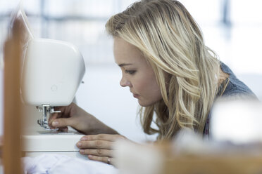 Young woman putting thread into a sewing machine - ZEF003684