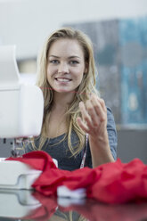Porträt einer lächelnden jungen Frau bei der Arbeit mit einer Nähmaschine - ZEF003688