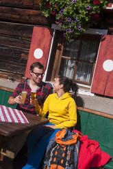 Österreich, Altenmarkt-Zauchensee, junges Paar mit Biergläsern vor einer Almhütte sitzend - HHF005158