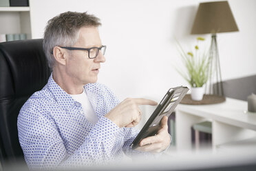 Geschäftsmann bei der Arbeit mit einem digitalen Tablet im Home Office - SEGF000257